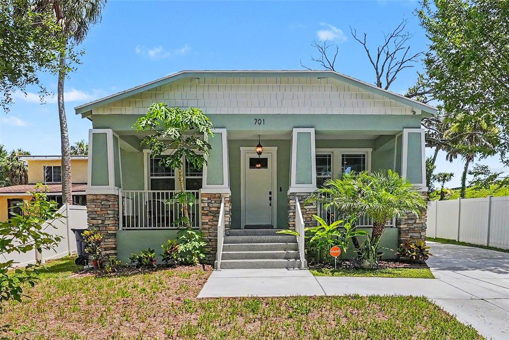 A light green bungalow with a stone-accented porch, white railings, and a concrete walkway — 701 E HOLLYWOOD STREET, TAMPA, FL