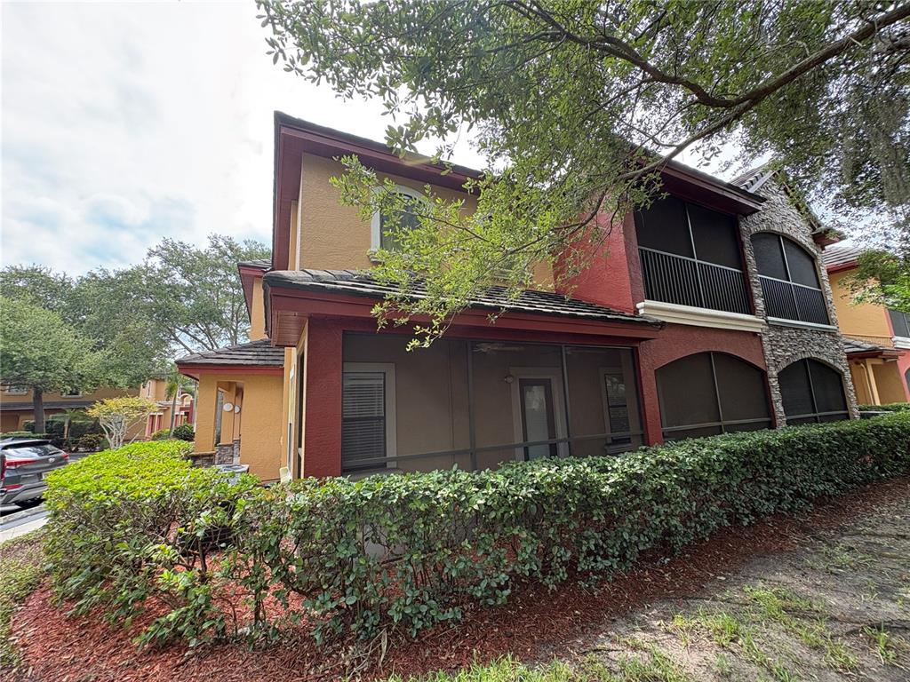 A two-story building with a screened-in patio, stucco walls, and stone accents — 2277 CHIANTI PLACE UNIT 37, PALM HARBOR, FL