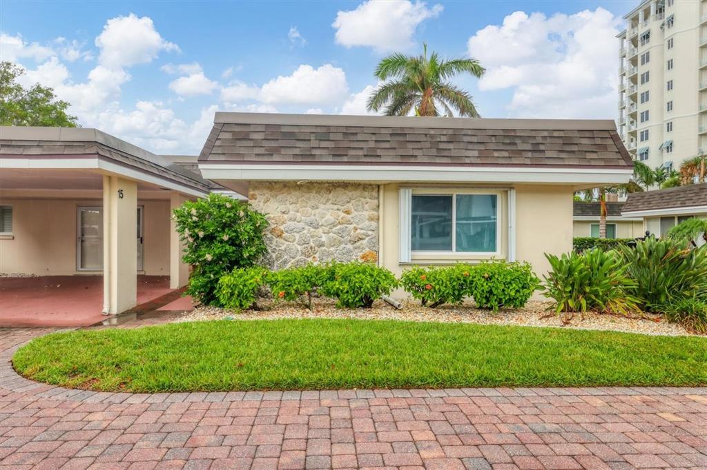 A single-story house with a stone facade, a shingled roof, and a paved driveway — 1900 BENJAMIN FRANKLIN DRIVE UNIT V-15, SARASOTA, FL