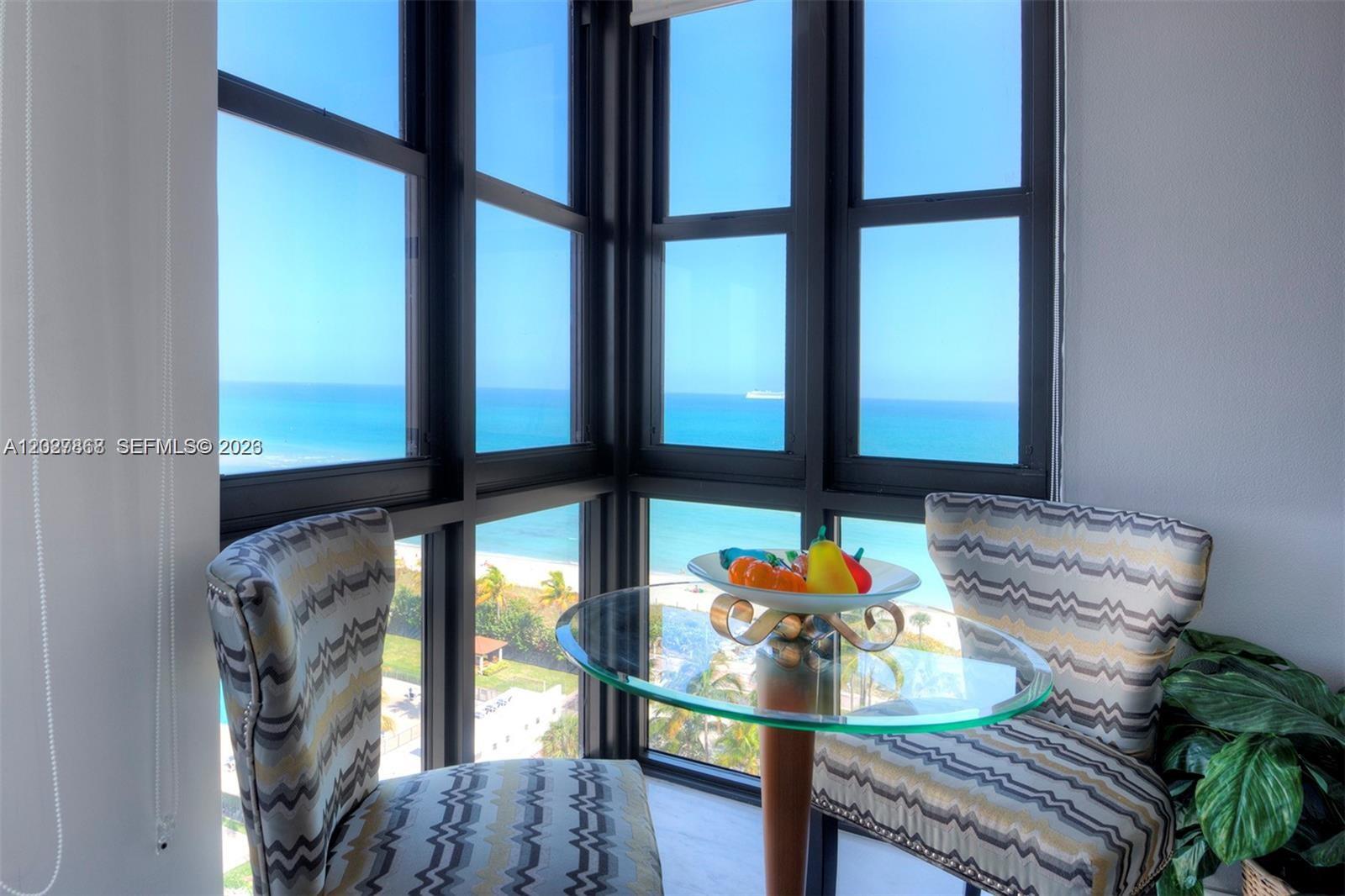 A small dining nook features two patterned chairs and a glass table overlooking the ocean — 2555 Collins Ave # 1400, Miami Beach FL 33140, MIAMI BEACH, FL
