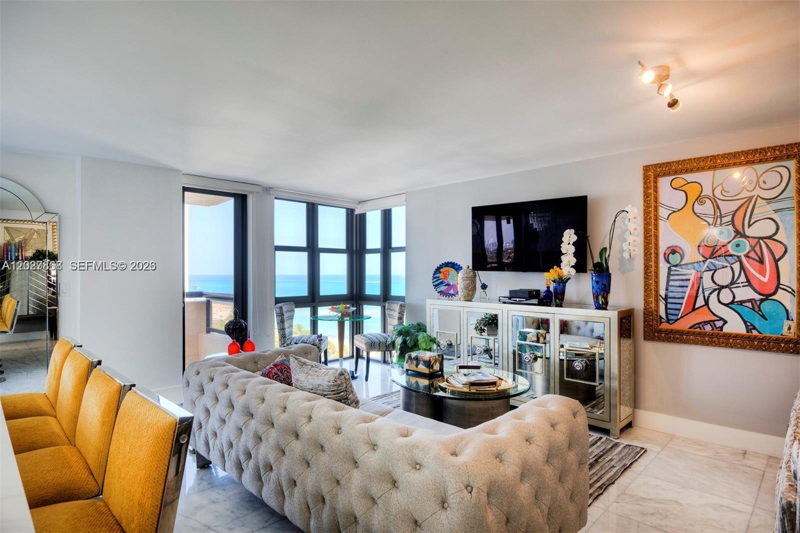 A living room features a tufted sofa, yellow chairs, mirrored furniture, and ocean views — 2555 Collins Ave # 1400, Miami Beach FL 33140, MIAMI BEACH, FL