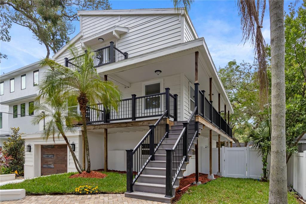 A white house with a raised wooden deck, black railings, and an outdoor staircase — 3232 W OAKELLAR AVENUE, TAMPA, FL