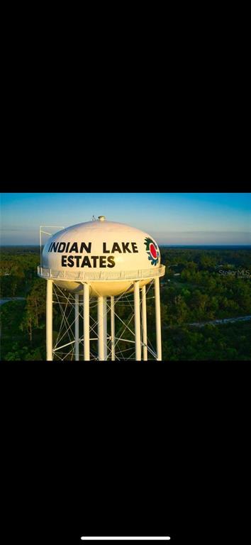 A white water tower with the text Indian Lake Estates stands above a forested landscape — 414 CAMELLIA DRIVE, INDIAN LAKE ESTATES, FL