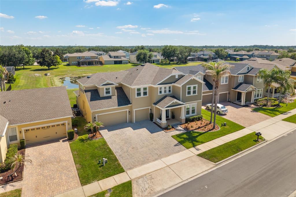 An aerial view of a two-story tan suburban house with a paved driveway and garage — 11716 SHELTERING PINE DRIVE, ORLANDO, FL