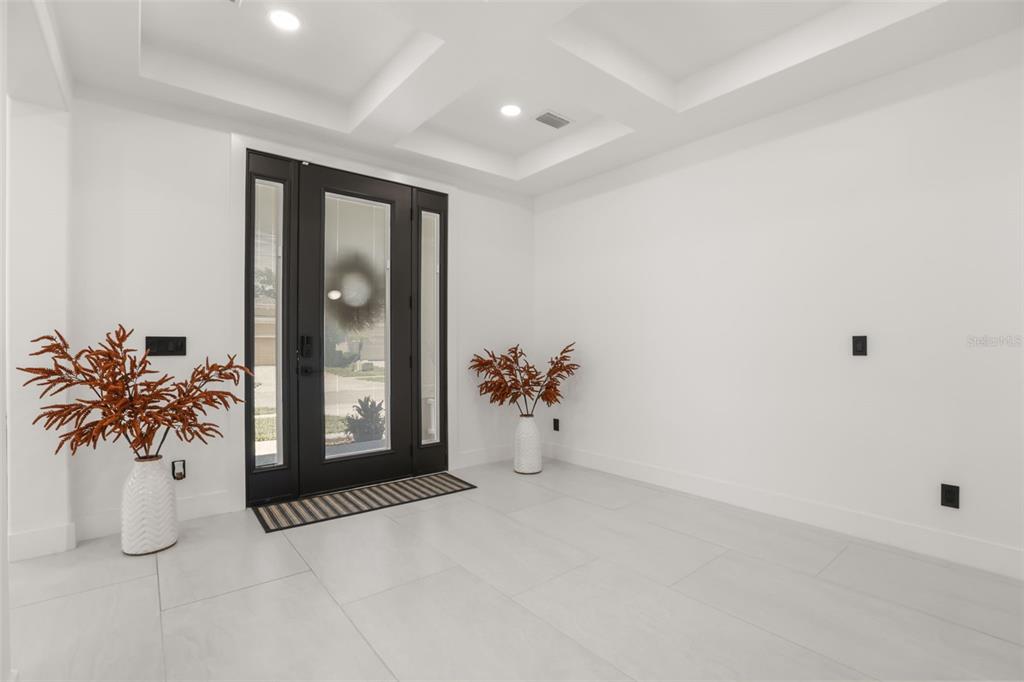 An entryway with white tile floors, a black front door, and two potted plants — 11716 SHELTERING PINE DRIVE, ORLANDO, FL