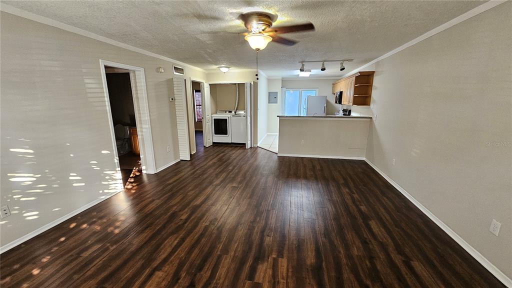 A living room with dark wood-look flooring, a ceiling fan, and an open kitchen area — 3651 N GOLDENROD ROAD UNIT A103, WINTER PARK, FL