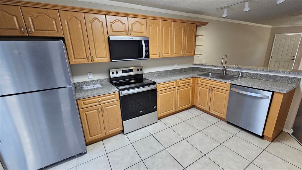 A kitchen features light wood cabinets, stainless steel appliances, and gray speckled countertops — 3651 N GOLDENROD ROAD UNIT A103, WINTER PARK, FL
