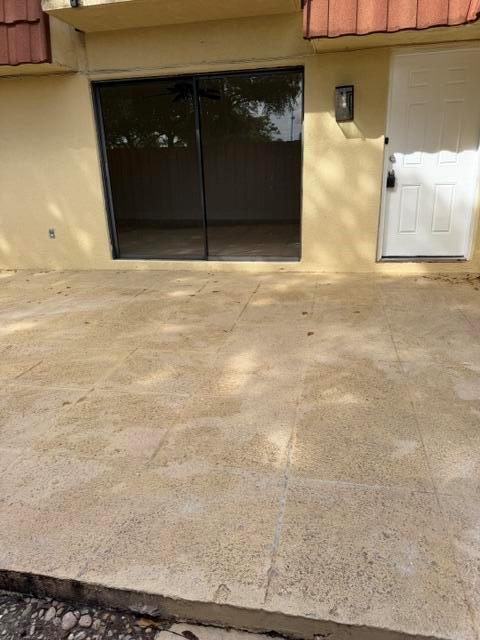 A concrete patio sits in front of a sliding glass door and a white door — 3001 San Clara Drive # a, Delray Beach FL 33445, DELRAY BEACH, FL