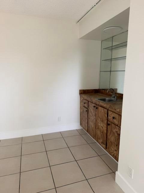 A small wet bar area features wood-grain cabinets, a sink, and mirrored glass shelving — 3001 San Clara Drive # a, Delray Beach FL 33445, DELRAY BEACH, FL