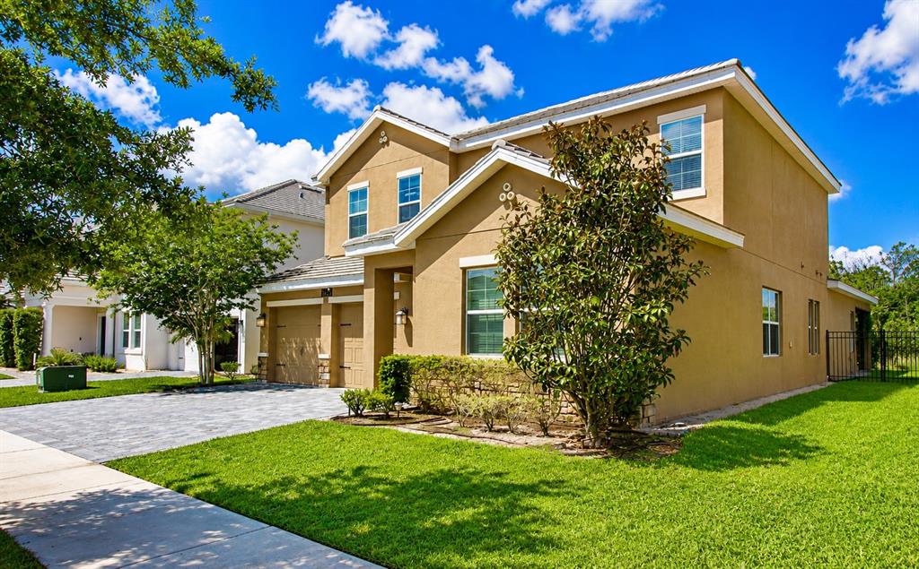 A two-story tan stucco house with a paved driveway and a green lawn — 11620 SATIRE STREET, ORLANDO, FL