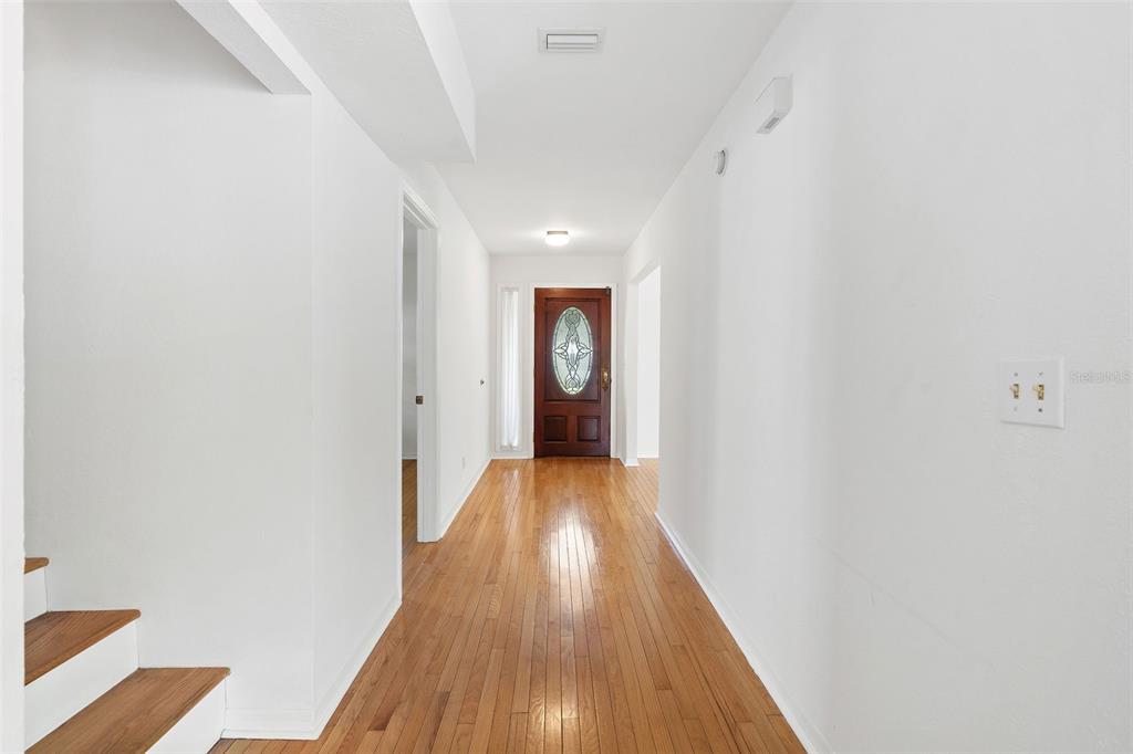 A bright hallway features hardwood floors, white walls, and a wooden front door with glass — 325 17TH AVENUE NE, ST PETERSBURG, FL