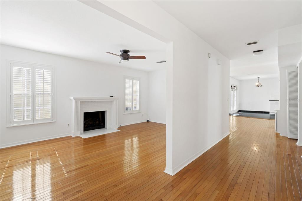 A living room with a fireplace and hardwood floors opens into a dining area — 325 17TH AVENUE NE, ST PETERSBURG, FL