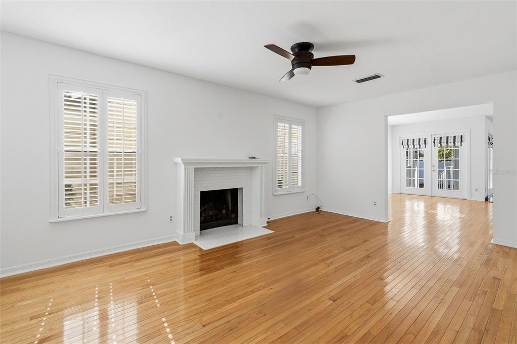 A living room features hardwood floors, a white brick fireplace, and a ceiling fan — 325 17TH AVENUE NE, ST PETERSBURG, FL