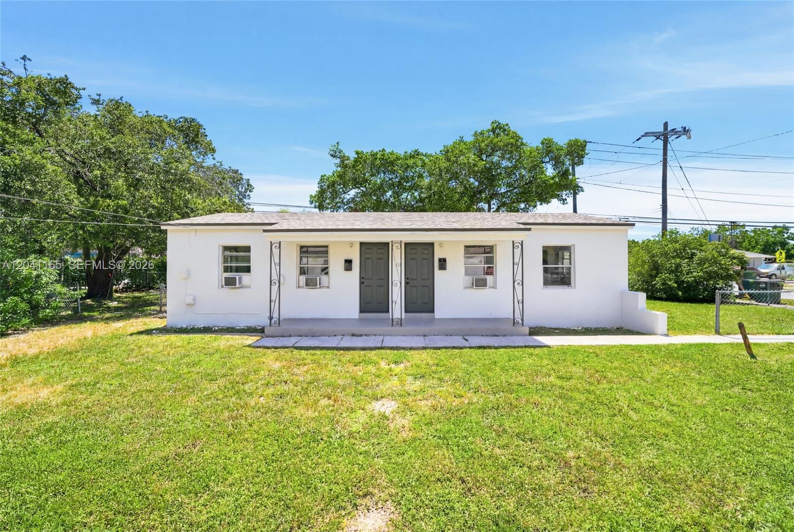 A single-story white duplex with two front doors and a covered porch sits on a lawn — 1992 NW 56th St, Miami FL 33142, MIAMI, FL