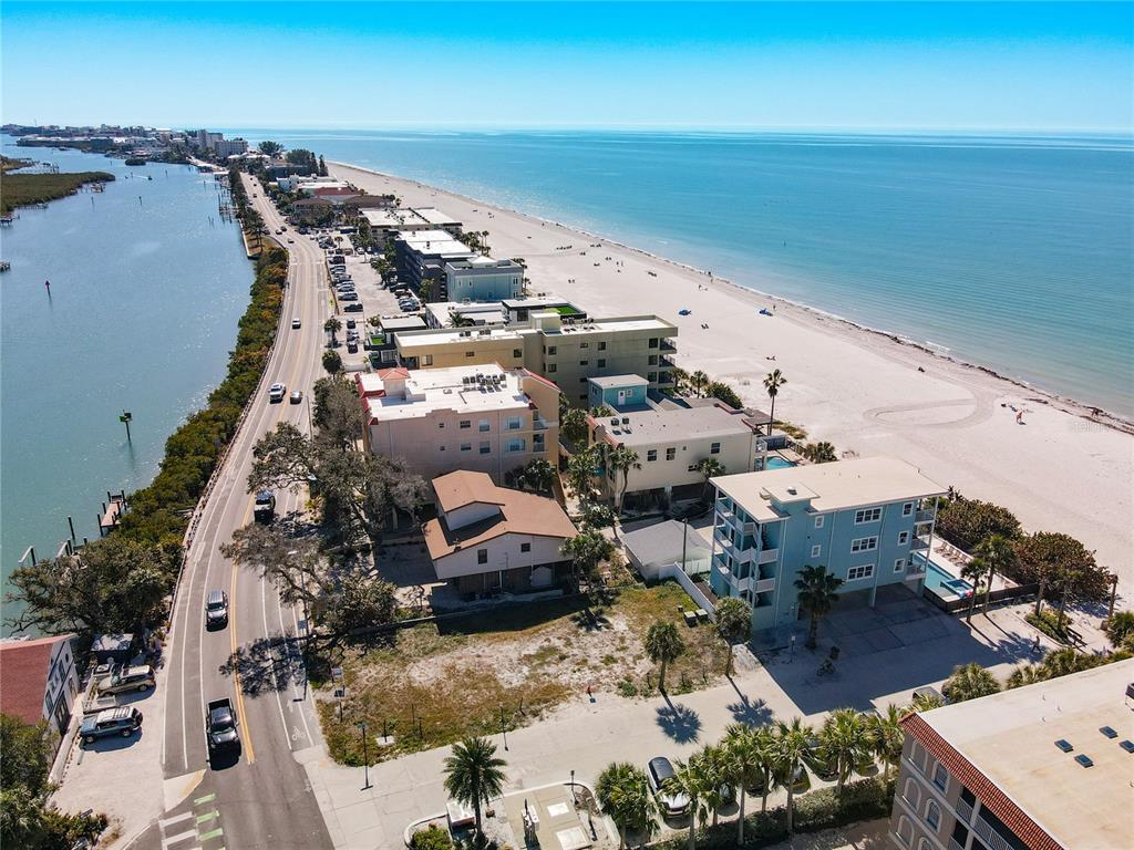 An aerial view shows a coastal road separating a bay from a sandy beach — 78 GULF BOULEVARD UNIT 5, INDIAN ROCKS BEACH, FL
