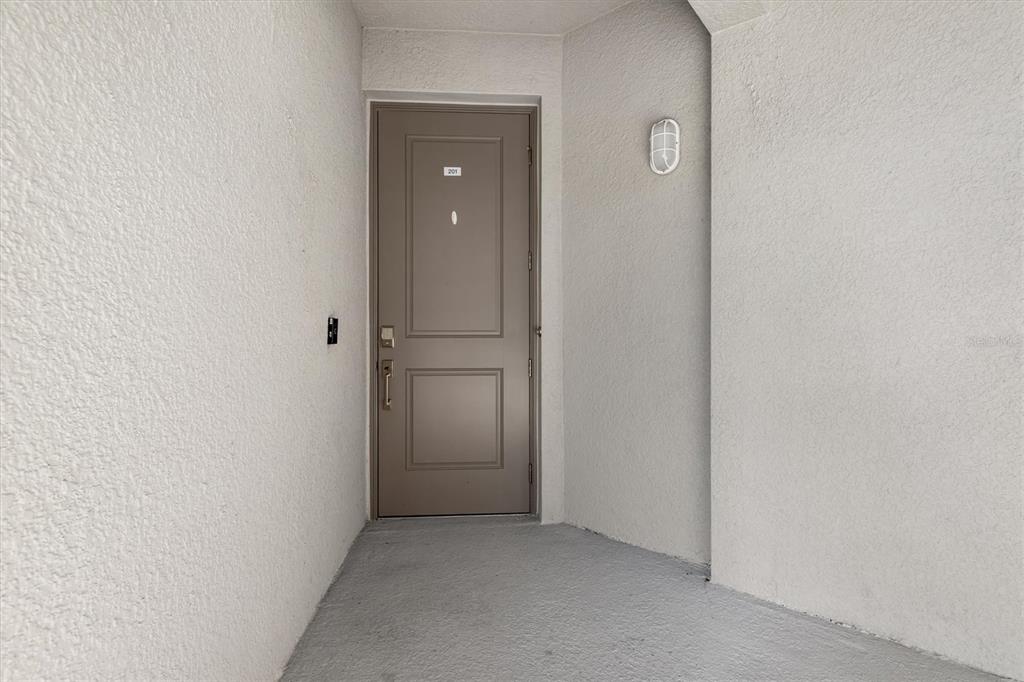 A brown front door with the number 201 is set into a textured white wall — 17565 OPAL SAND DRIVE UNIT 201, VENICE, FL