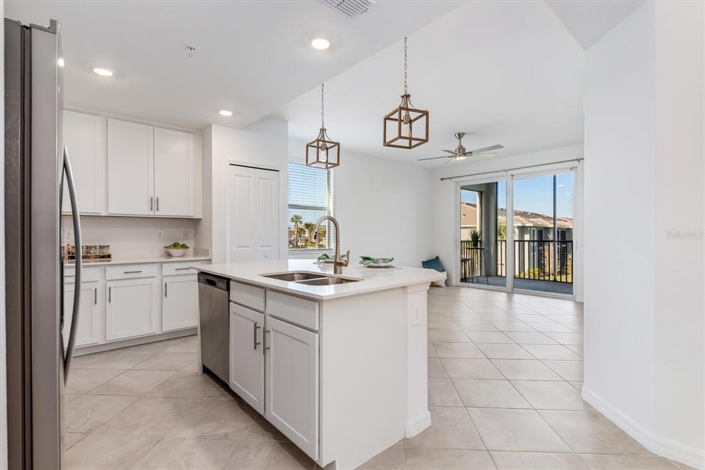 A kitchen with white cabinets, a central island, and an adjacent living area with balcony — 17565 OPAL SAND DRIVE UNIT 201, VENICE, FL