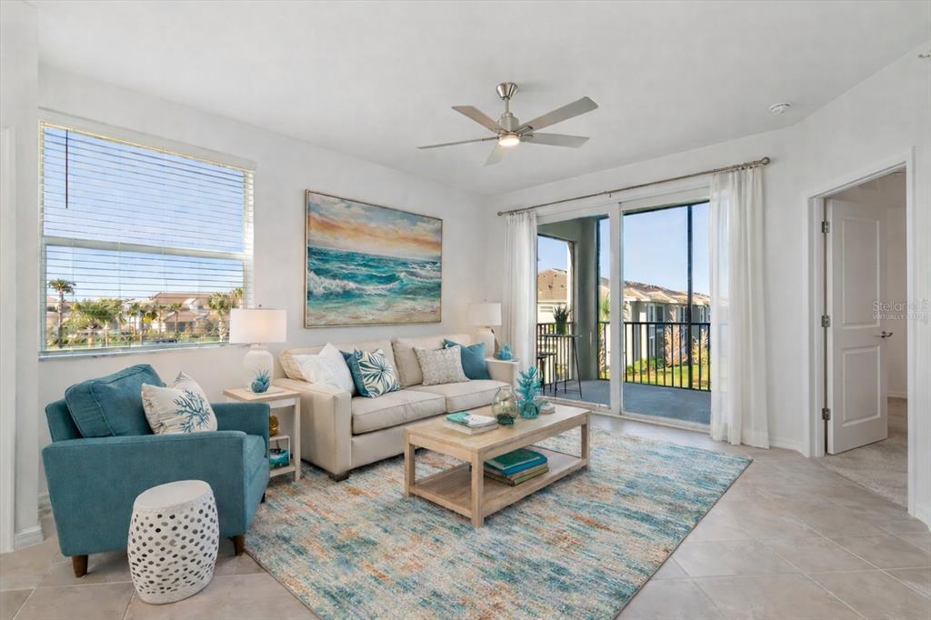 A living room features a beige sofa, blue armchair, area rug, and sliding glass balcony doors — 17565 OPAL SAND DRIVE UNIT 201, VENICE, FL