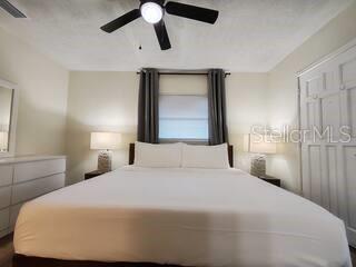 A bedroom features a bed with white linens, two bedside lamps, and a ceiling fan — 5810 N 19TH STREET, TAMPA, FL