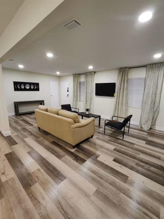 A living room features a tan sofa, two accent chairs, and wood-look flooring — 5810 N 19TH STREET, TAMPA, FL