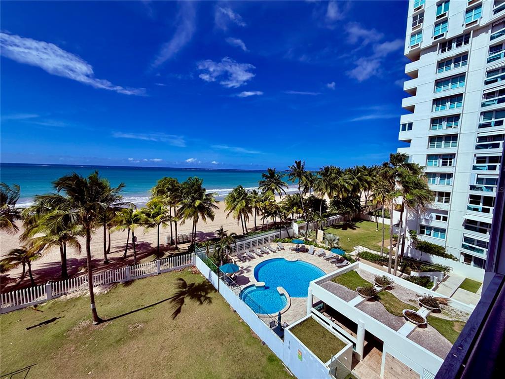 An elevated view of a beach, palm trees, a swimming pool, and a tall building — 1 HORIZONTE UNIT 514, CAROLINA, PR