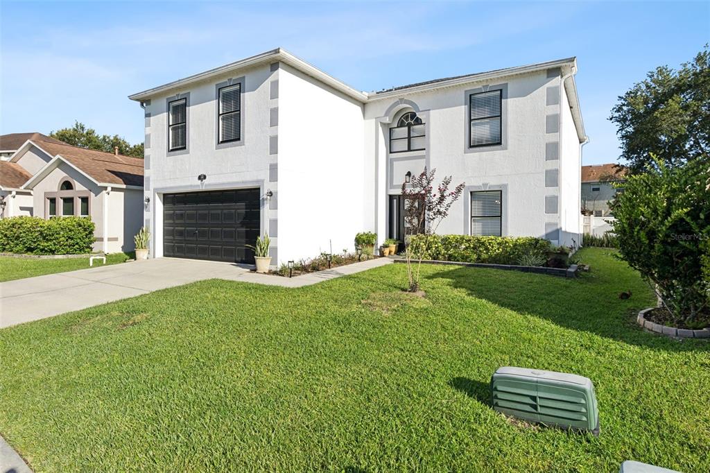 A two-story white house with a black garage door and a front lawn — 4981 SPINET DRIVE, MELBOURNE, FL