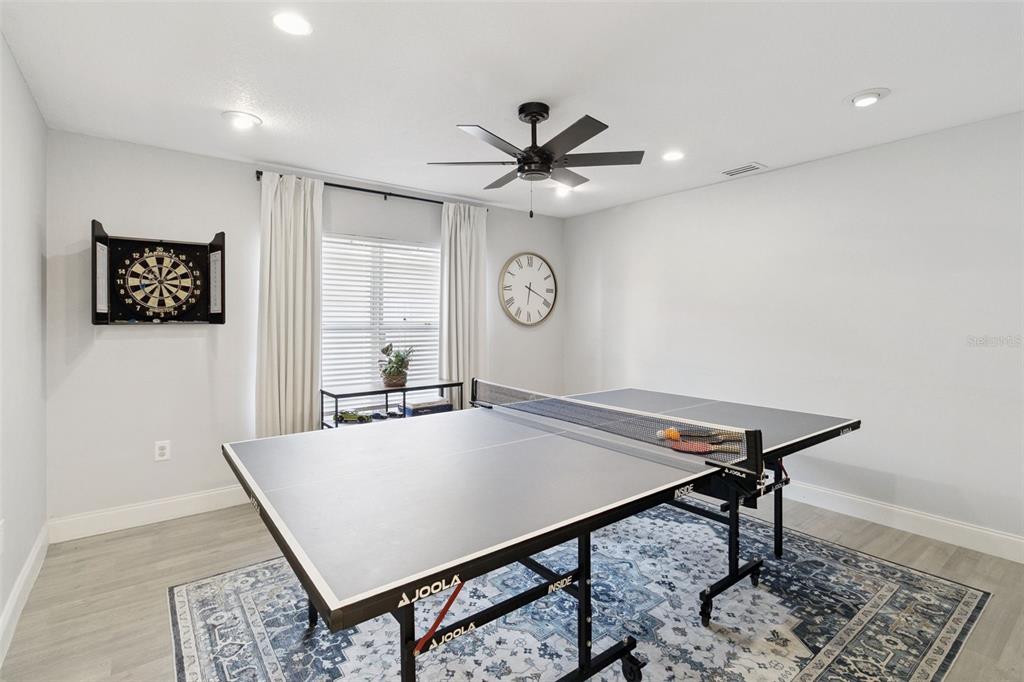 A game room features a ping pong table, a dartboard, and a wall clock — 4981 SPINET DRIVE, MELBOURNE, FL