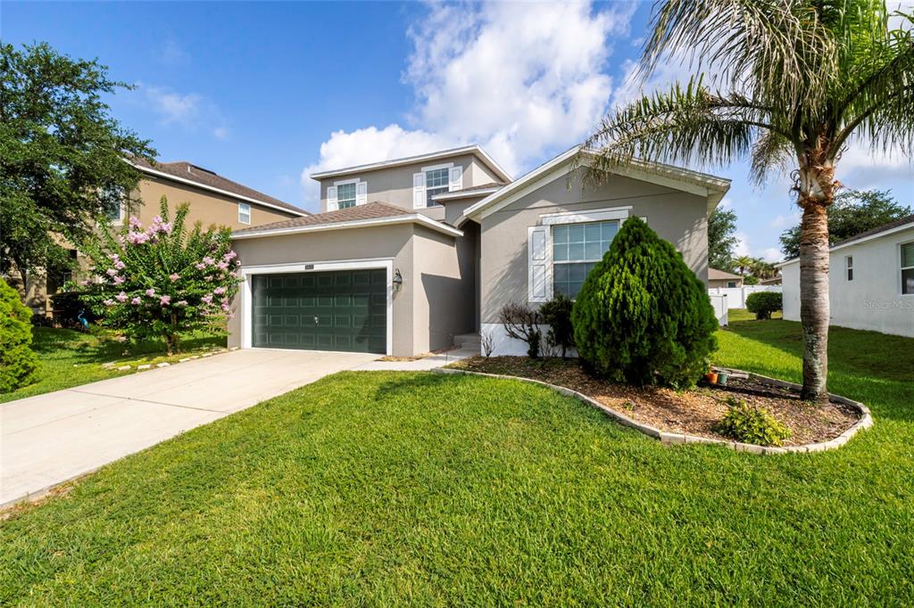 A two-story suburban house with a gray exterior, a two-car garage, and a palm tree — 4841 HAVILLAND DRIVE, MOUNT DORA, FL