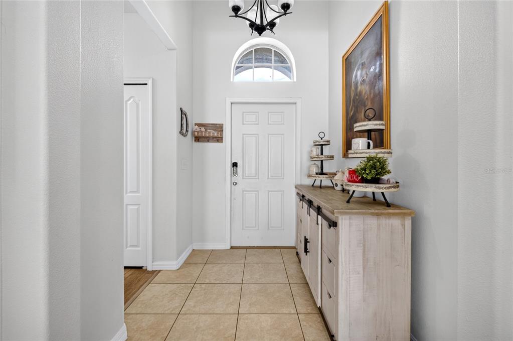 A bright entryway features a white front door, tile flooring, and a rustic wooden console — 4841 HAVILLAND DRIVE, MOUNT DORA, FL