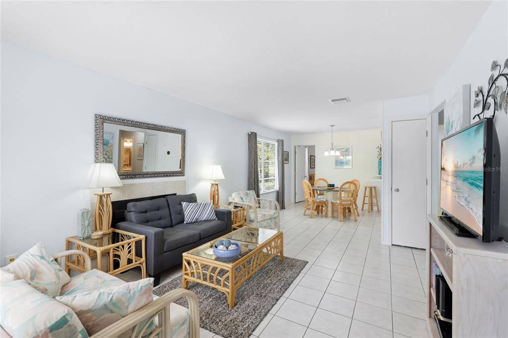 A living room with tile floors, a gray sofa, a rattan coffee table, and dining area — 3634 59TH AVENUE W, BRADENTON, FL
