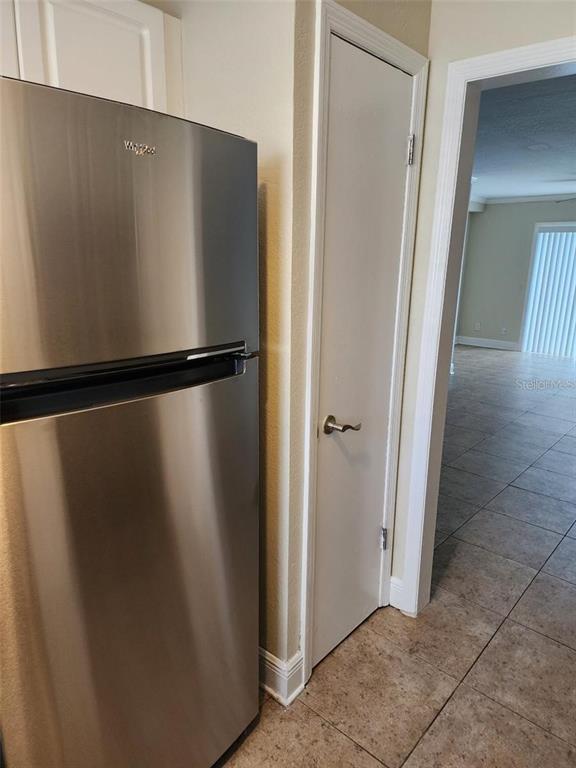 A stainless steel refrigerator stands next to a white door in a tiled kitchen — 13698 ORANGE SUNSET DRIVE, TAMPA, FL