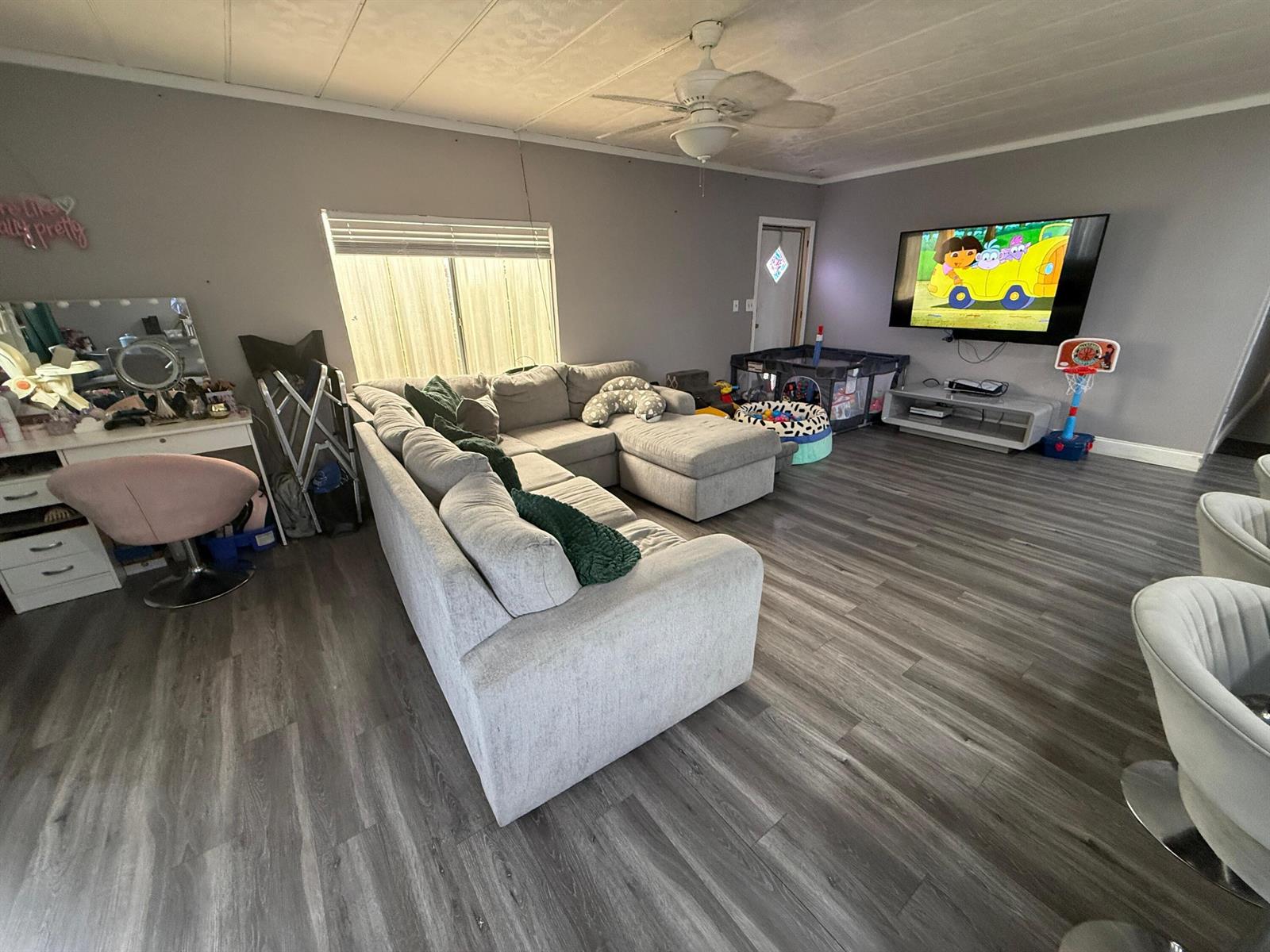 A living room with gray walls, wood-look flooring, a sectional sofa, and a wall-mounted television — 4707 Nancy Drive # 757, FL 33463, FL
