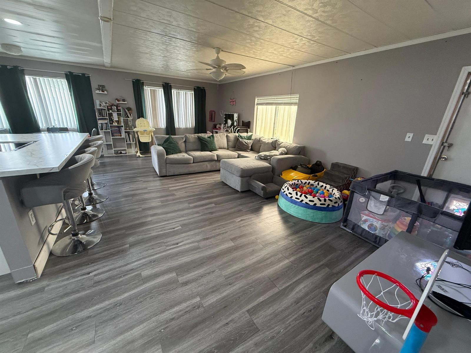 A living room with gray flooring, a sectional sofa, a kitchen island, and children's toys — 4707 Nancy Drive # 757, FL 33463, FL