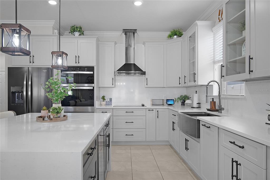 A modern kitchen features white cabinetry, a large island, stainless steel appliances, and quartz countertops — 1796 CAYMAN COVE CIRCLE, ST CLOUD, FL