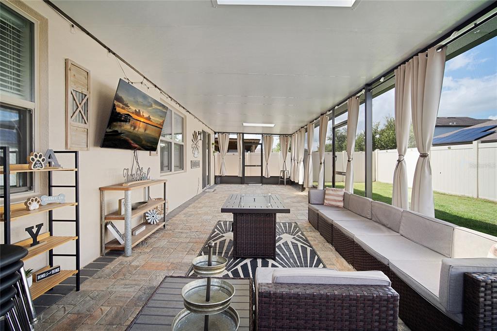 A covered outdoor patio features a television, wicker furniture, and a stone-paver floor — 1796 CAYMAN COVE CIRCLE, ST CLOUD, FL
