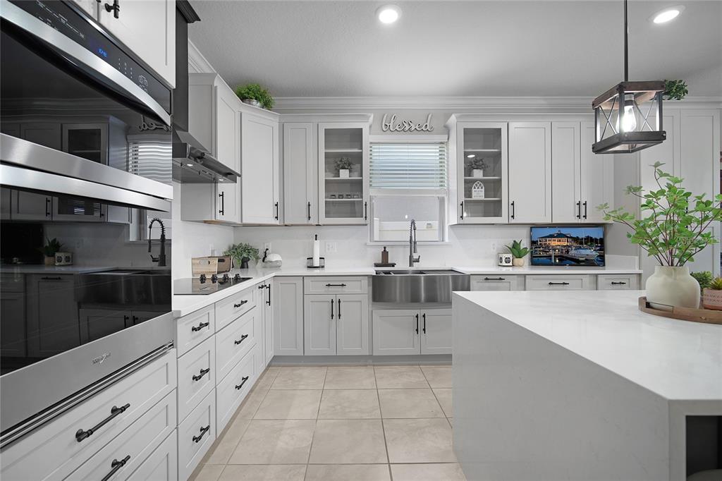 A modern kitchen features white cabinetry, stainless steel appliances, a farmhouse sink, and a quartz island — 1796 CAYMAN COVE CIRCLE, ST CLOUD, FL