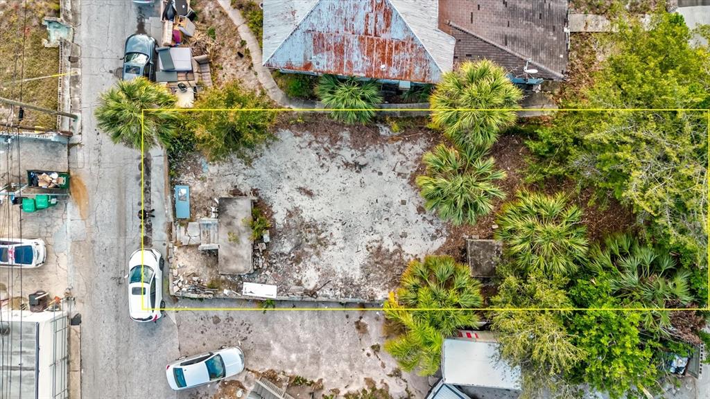 An aerial view shows a vacant, sandy lot outlined in yellow with several palm trees — ATHENS STREET, TARPON SPRINGS, FL