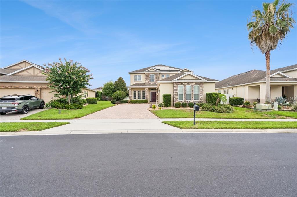 A two-story suburban house with a paved driveway, stone facade, and a palm tree — 2045 SANDY GARDEN LANE, WINTER GARDEN, FL