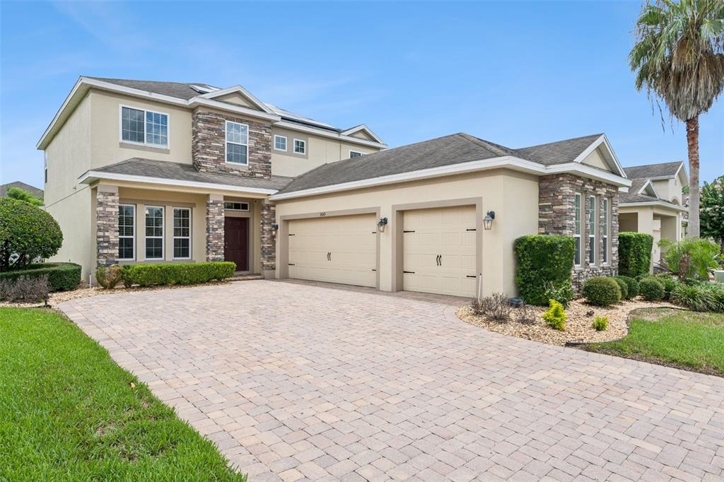 A two-story house with a stone facade, beige stucco, and a paved driveway — 2045 SANDY GARDEN LANE, WINTER GARDEN, FL