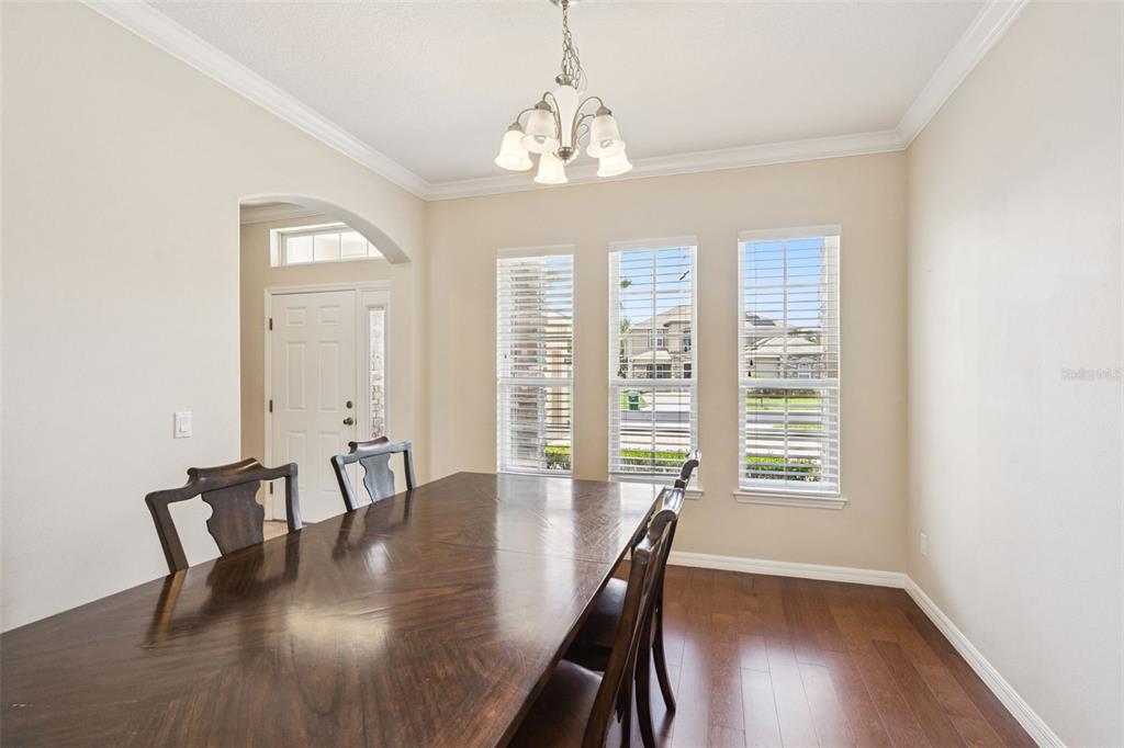 A dining room features a dark wood table, hardwood floors, and three windows with blinds — 2045 SANDY GARDEN LANE, WINTER GARDEN, FL