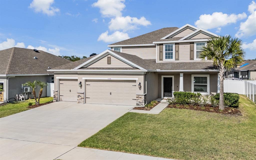 A two-story suburban house features a beige exterior, a three-car garage, and a palm tree — 13418 LAKEVIEW OAKS LANE, RIVERVIEW, FL