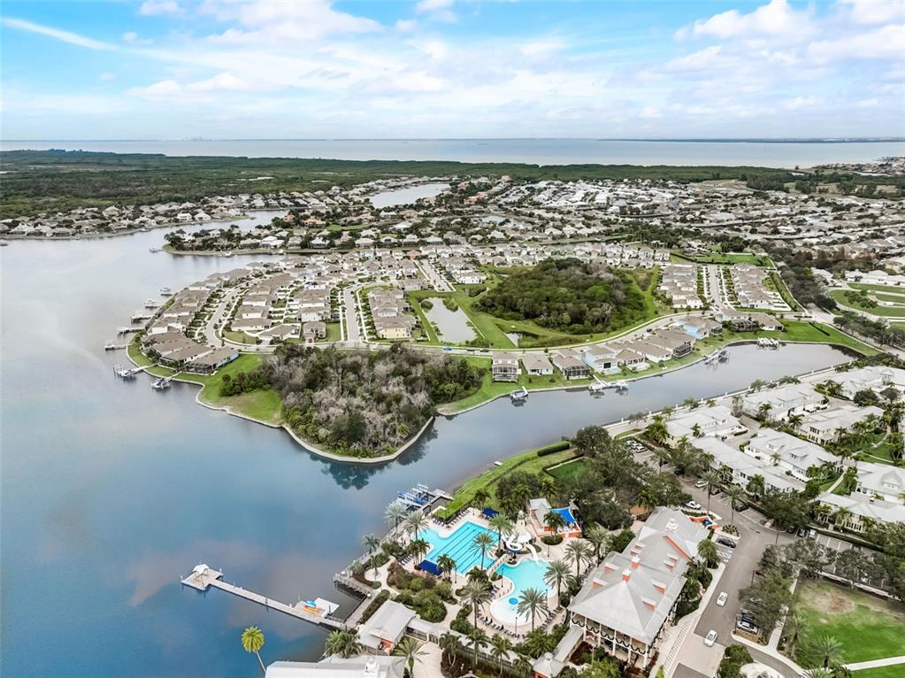 An aerial view shows a residential community with a pool, clubhouse, and waterfront docks — 5413 WISHING ARCH DRIVE, APOLLO BEACH, FL