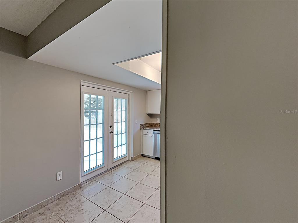 A kitchen area features tiled floors, white cabinets, and French doors leading outdoors — 11532 BENBOW COURT, ORLANDO, FL