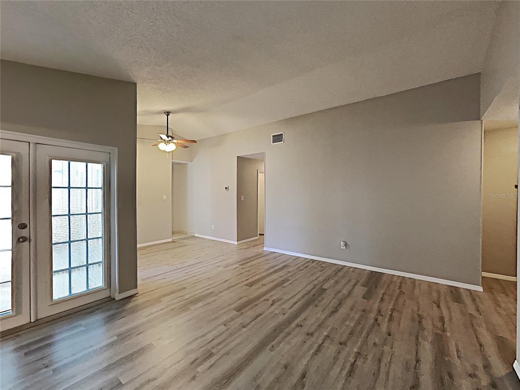 An interior view shows a living area with light wood-look flooring and vaulted ceilings — 11532 BENBOW COURT, ORLANDO, FL