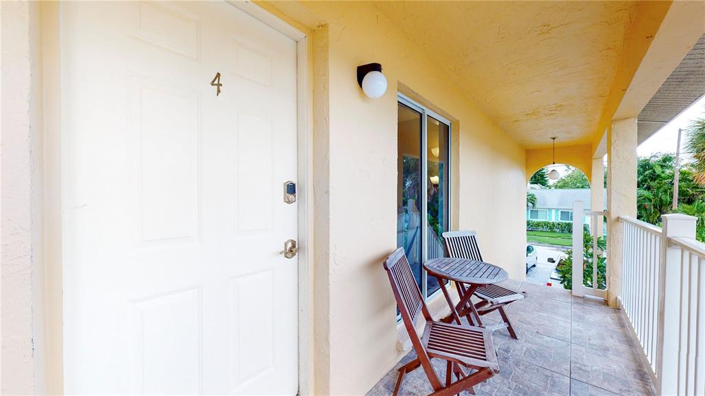 A white door marked with the number four opens onto a covered outdoor balcony — 7209 COQUINA WAY UNIT 4, ST PETE BEACH, FL
