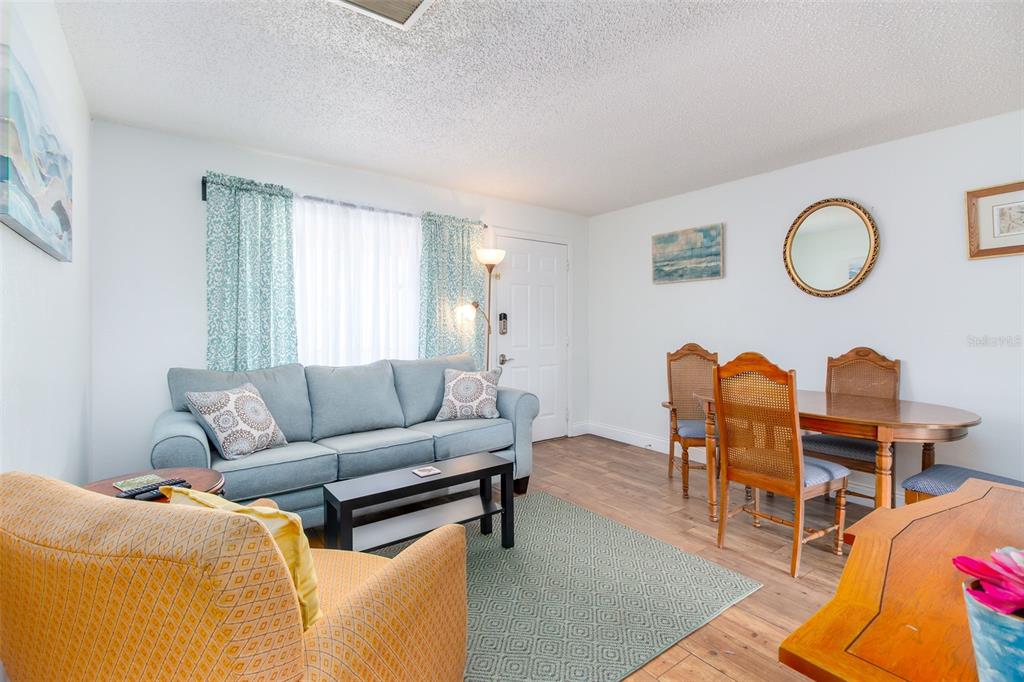 A living and dining area features a blue sofa, yellow armchair, and wood dining set — 7209 COQUINA WAY UNIT 4, ST PETE BEACH, FL