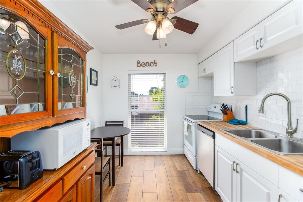 A kitchen features white cabinets, wood countertops, a dining table, and a ceiling fan — 7209 COQUINA WAY UNIT 4, ST PETE BEACH, FL