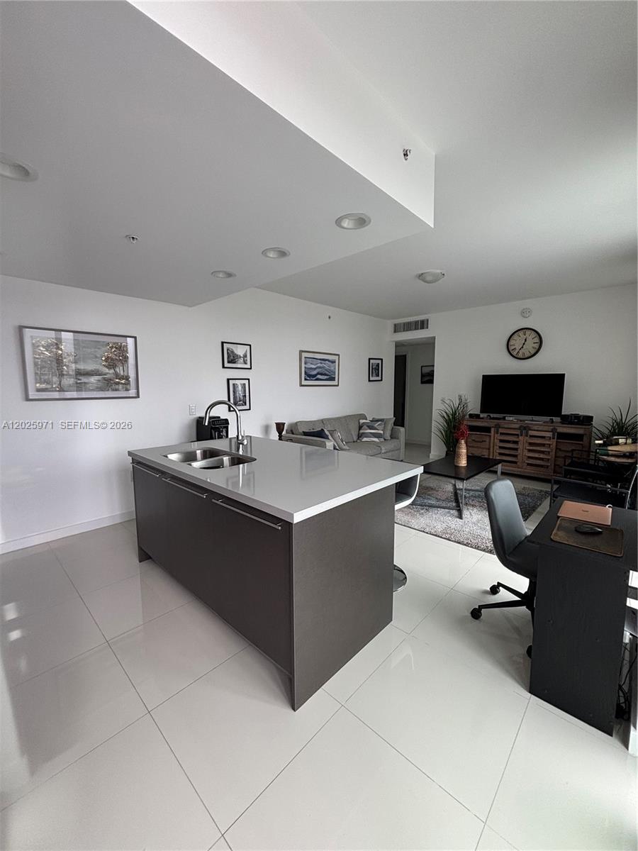 A modern kitchen island with a gray base sits in an open-concept living area — 7875 NW 107th Ave # 504, Doral FL 33178, DORAL, FL