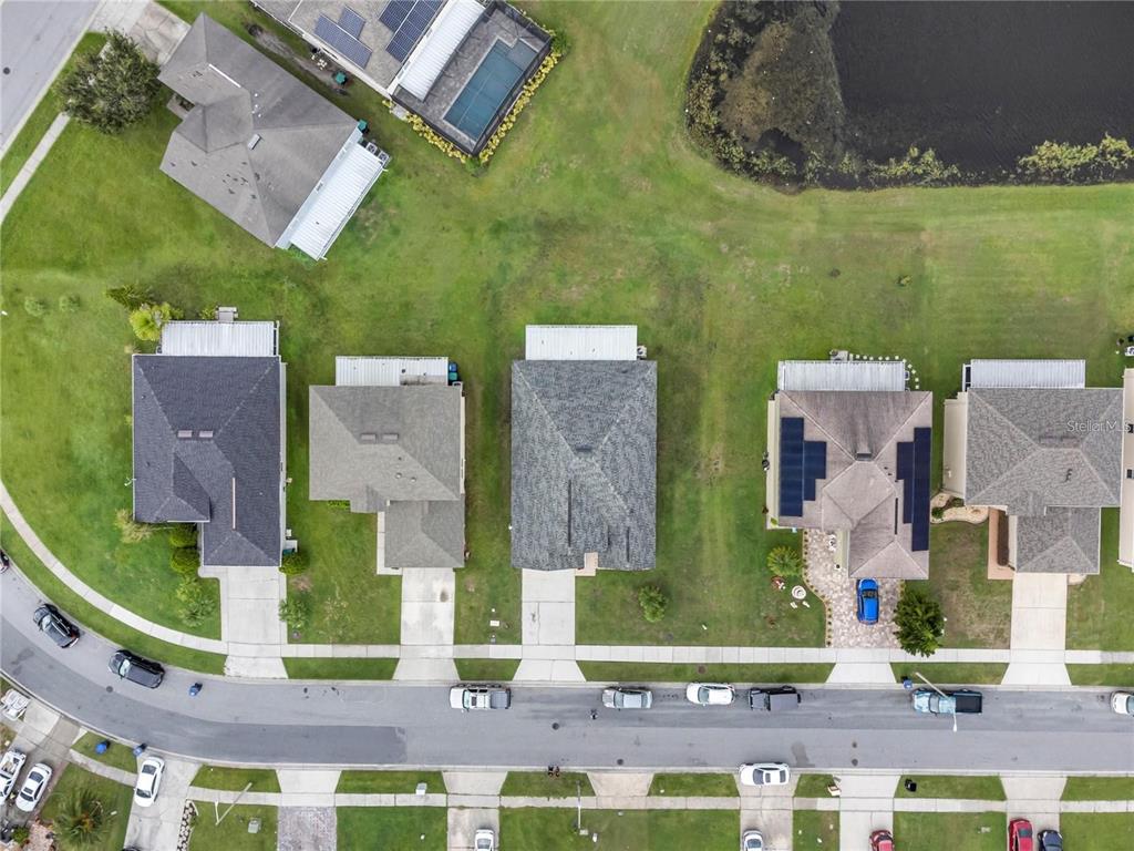 An aerial view shows a suburban street with several houses, driveways, and a nearby pond — 10354 LAXTON STREET, ORLANDO, FL