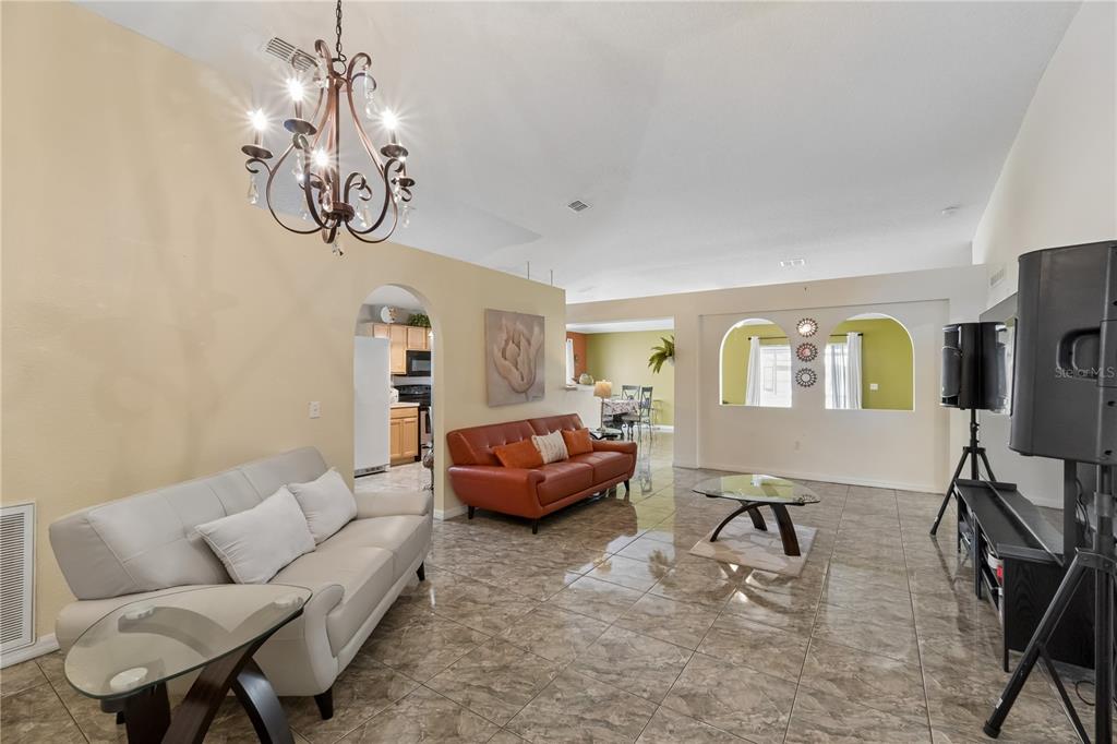 A living room with tiled floors, two sofas, a chandelier, and arched wall openings — 10354 LAXTON STREET, ORLANDO, FL